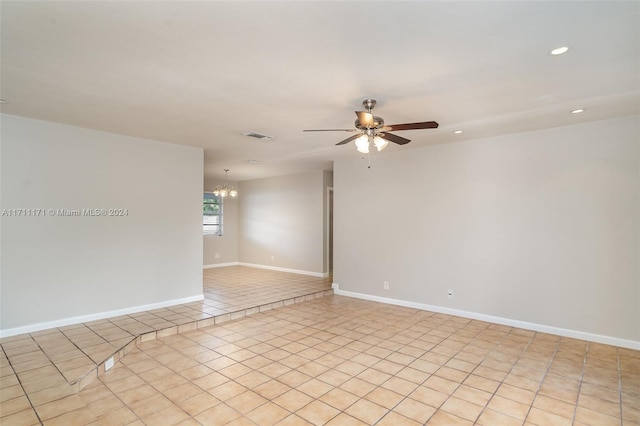 spare room with ceiling fan with notable chandelier and light tile patterned floors