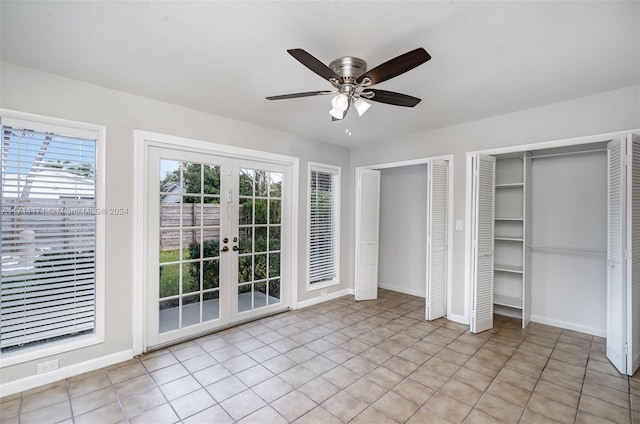 unfurnished bedroom with multiple closets, access to exterior, multiple windows, and french doors