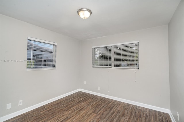 empty room featuring a healthy amount of sunlight and dark wood-type flooring