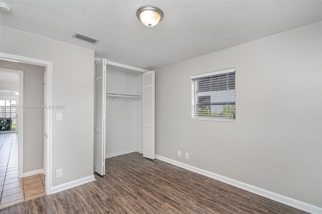 unfurnished bedroom with dark hardwood / wood-style flooring and a closet