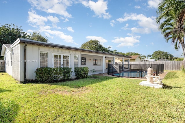 rear view of house featuring a fenced in pool and a yard