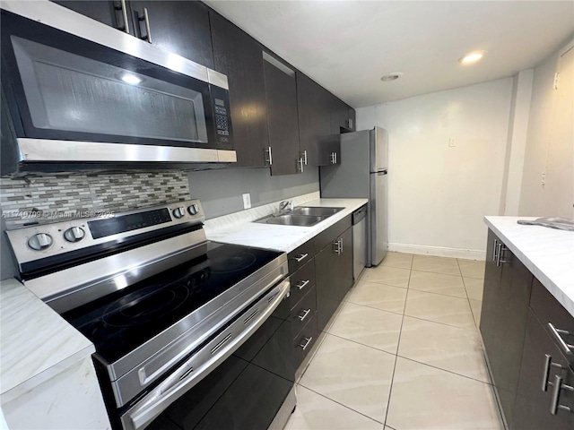 kitchen with light tile patterned floors, appliances with stainless steel finishes, sink, and backsplash