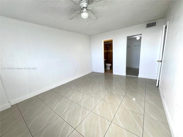 unfurnished bedroom featuring tile patterned flooring, a walk in closet, ceiling fan, a textured ceiling, and a closet