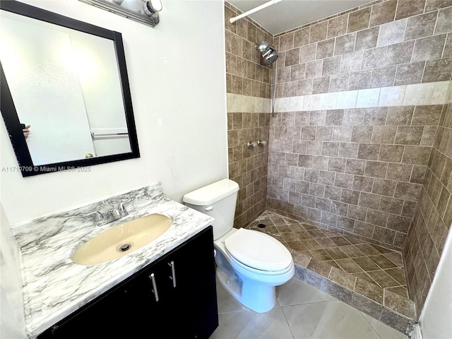 bathroom featuring vanity, tile patterned flooring, toilet, and tiled shower