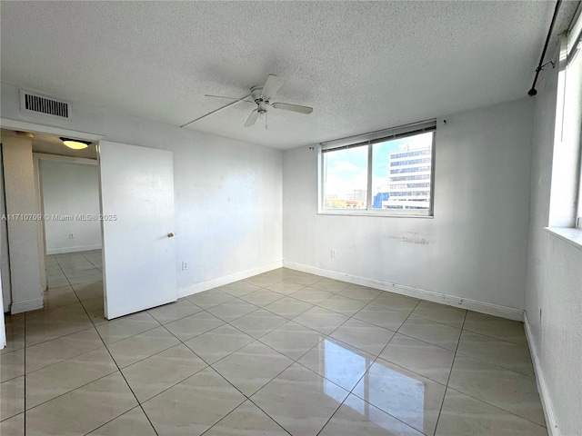 spare room with light tile patterned floors, a textured ceiling, and ceiling fan