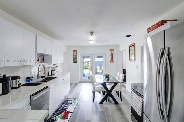 kitchen with sink, french doors, stainless steel appliances, light hardwood / wood-style flooring, and white cabinets