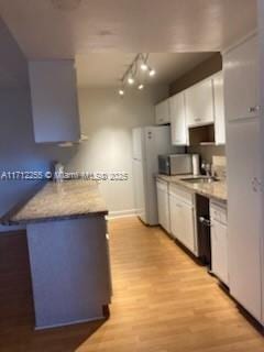 kitchen with sink, white cabinets, light hardwood / wood-style floors, and white appliances