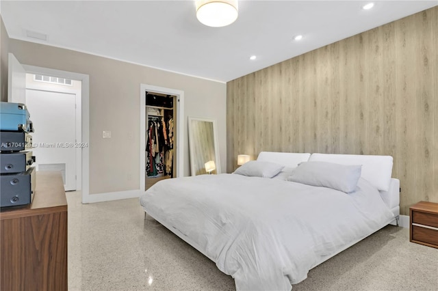 bedroom featuring a spacious closet, a closet, and wooden walls