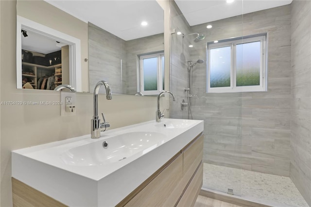 bathroom with vanity, tiled shower, and a wealth of natural light