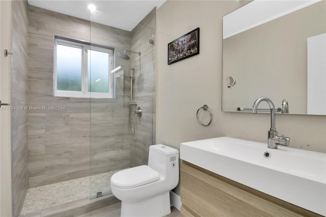 bathroom featuring tiled shower, hardwood / wood-style floors, vanity, and toilet