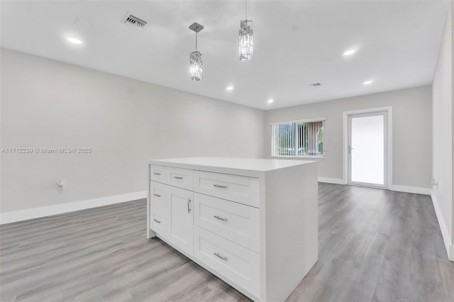 kitchen with white cabinetry, a kitchen island, hanging light fixtures, and light hardwood / wood-style floors