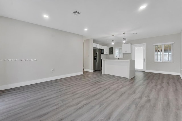 unfurnished living room with light hardwood / wood-style floors and sink