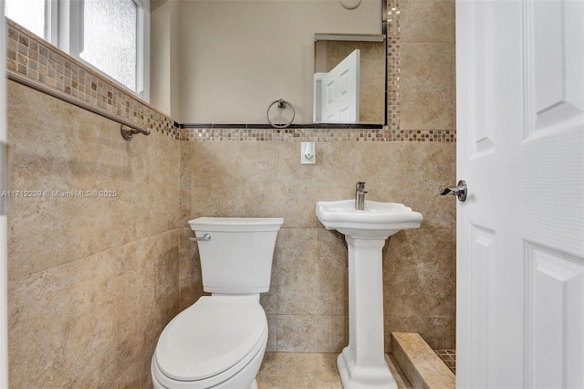 bathroom featuring tile walls and toilet