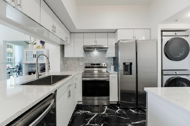 kitchen featuring white cabinetry, sink, tasteful backsplash, stacked washer and dryer, and appliances with stainless steel finishes