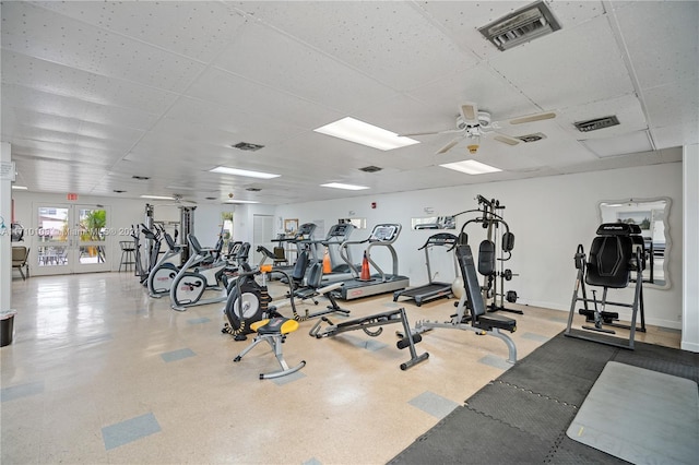 exercise room with a paneled ceiling, ceiling fan, and french doors