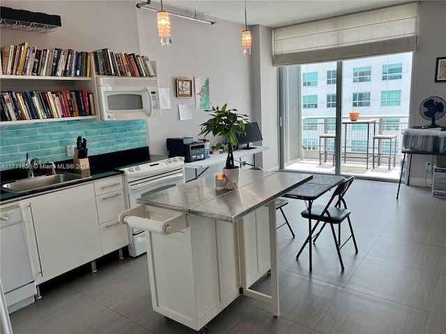 kitchen with backsplash, white appliances, sink, pendant lighting, and white cabinets