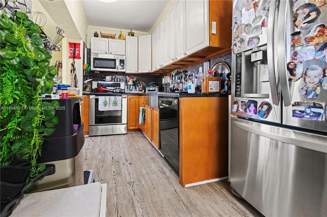 2716 Polk St, Hollywood, FL 33020 - kitchen featuring appliances with stainless steel finishes, light wood-style flooring, white cabinets, and dark countertops