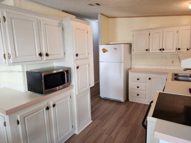 kitchen featuring white fridge, stove, white cabinetry, and sink