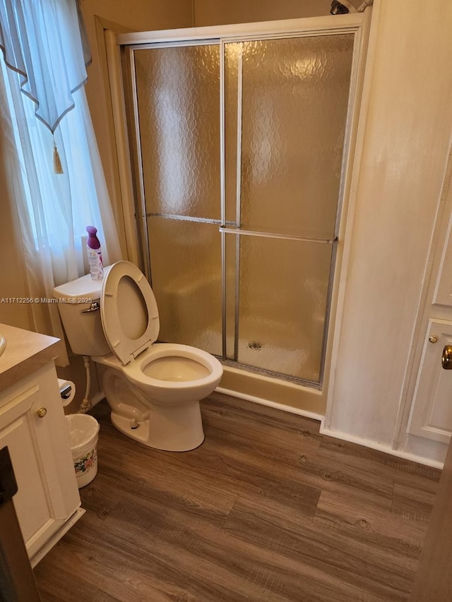 bathroom featuring wood-type flooring, vanity, toilet, and a shower with door