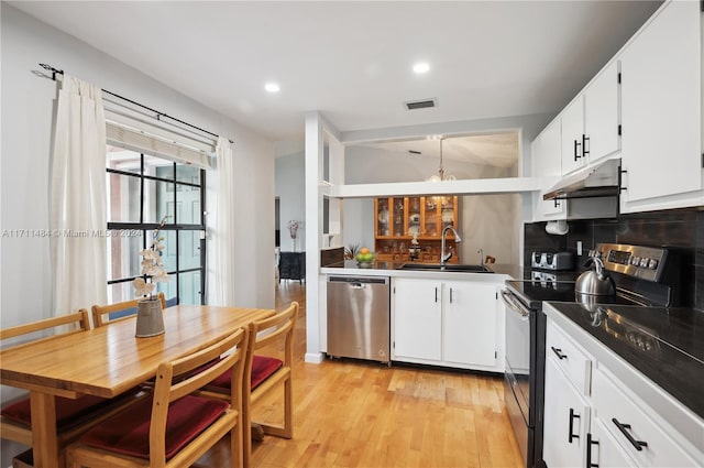 kitchen with white cabinets, sink, light hardwood / wood-style flooring, decorative backsplash, and stainless steel appliances