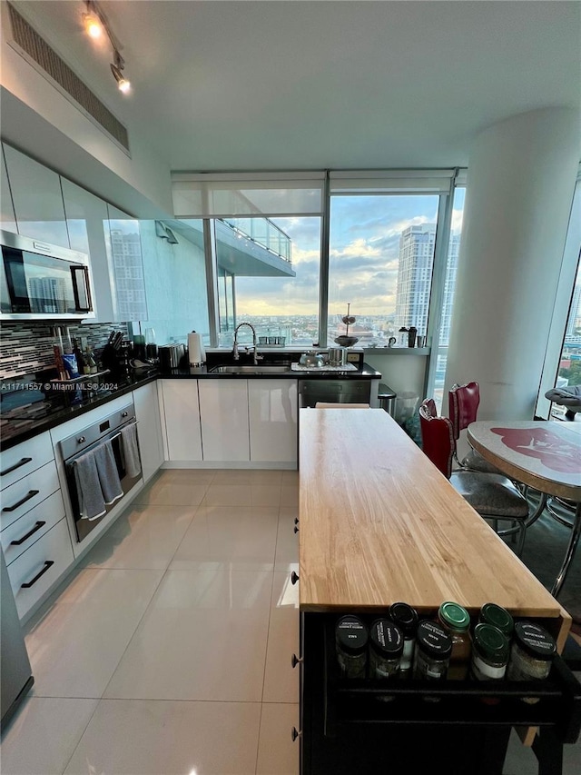 kitchen with white cabinets, sink, light tile patterned floors, butcher block countertops, and stainless steel appliances