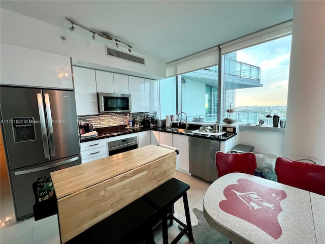 kitchen featuring tasteful backsplash, sink, white cabinets, and appliances with stainless steel finishes