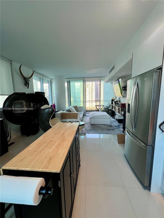 kitchen with butcher block counters, stainless steel fridge with ice dispenser, and light tile patterned flooring