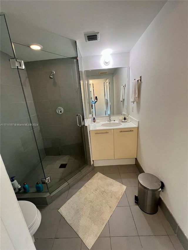 bathroom featuring toilet, vanity, tile patterned floors, and a shower with shower door