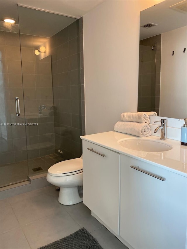 bathroom featuring tile patterned flooring, vanity, toilet, and an enclosed shower