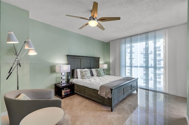 bedroom featuring ceiling fan, access to exterior, a wall of windows, and a textured ceiling