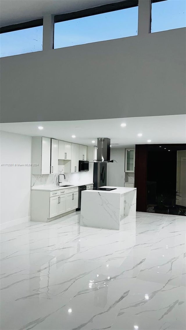 kitchen with white cabinetry, black refrigerator, decorative backsplash, wall chimney exhaust hood, and sink