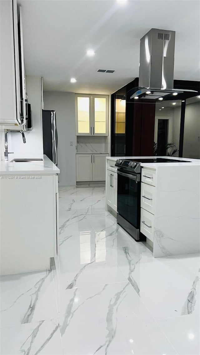 kitchen featuring island exhaust hood, white cabinetry, light stone countertops, range with electric cooktop, and black refrigerator