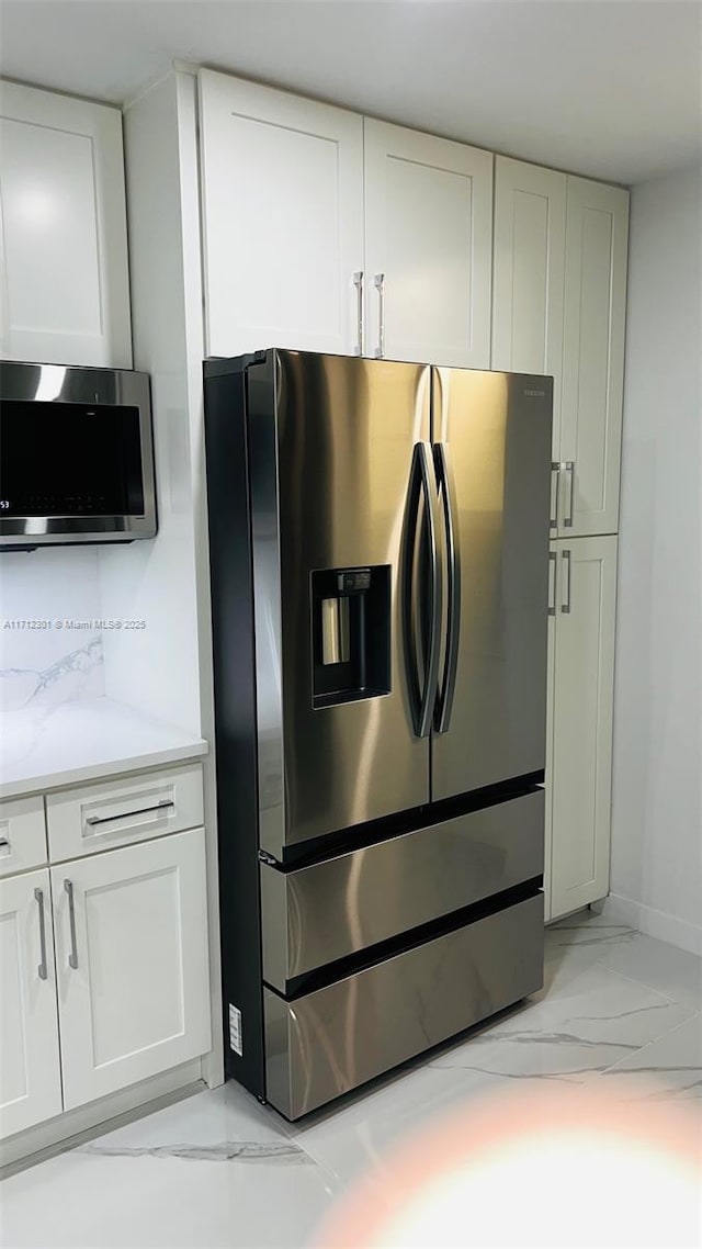 room details featuring light stone counters, stainless steel appliances, and white cabinetry