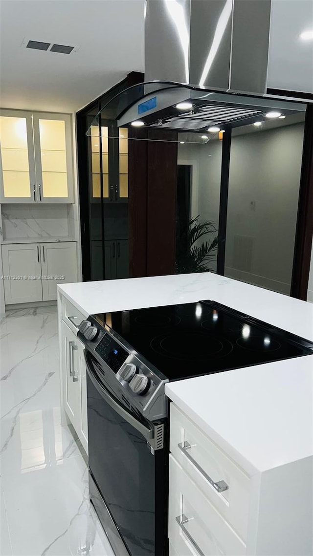 kitchen with island range hood, white cabinets, and electric range