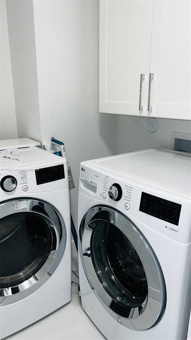 washroom featuring light tile patterned floors, washing machine and dryer, and cabinets