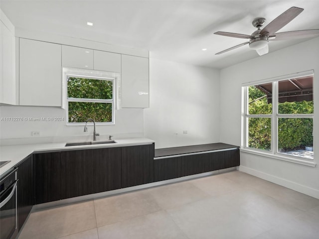 kitchen featuring white cabinets, stainless steel oven, ceiling fan, and sink