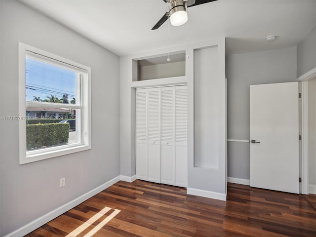 unfurnished bedroom with ceiling fan, a closet, and dark wood-type flooring