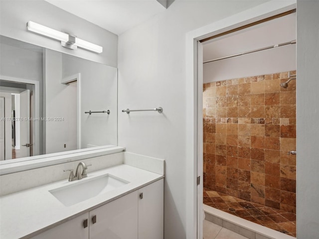 bathroom with tiled shower, vanity, and tile patterned floors