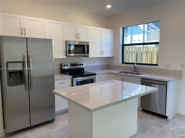 kitchen with a center island, sink, stainless steel appliances, white cabinets, and light tile patterned flooring