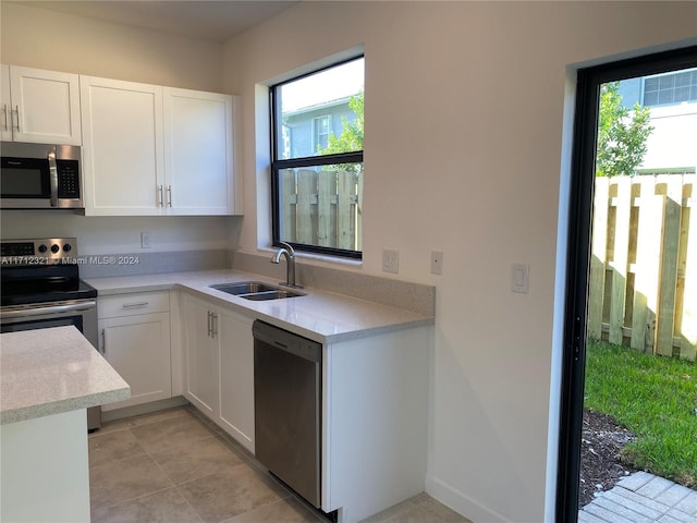 kitchen with a wealth of natural light, white cabinetry, sink, and appliances with stainless steel finishes