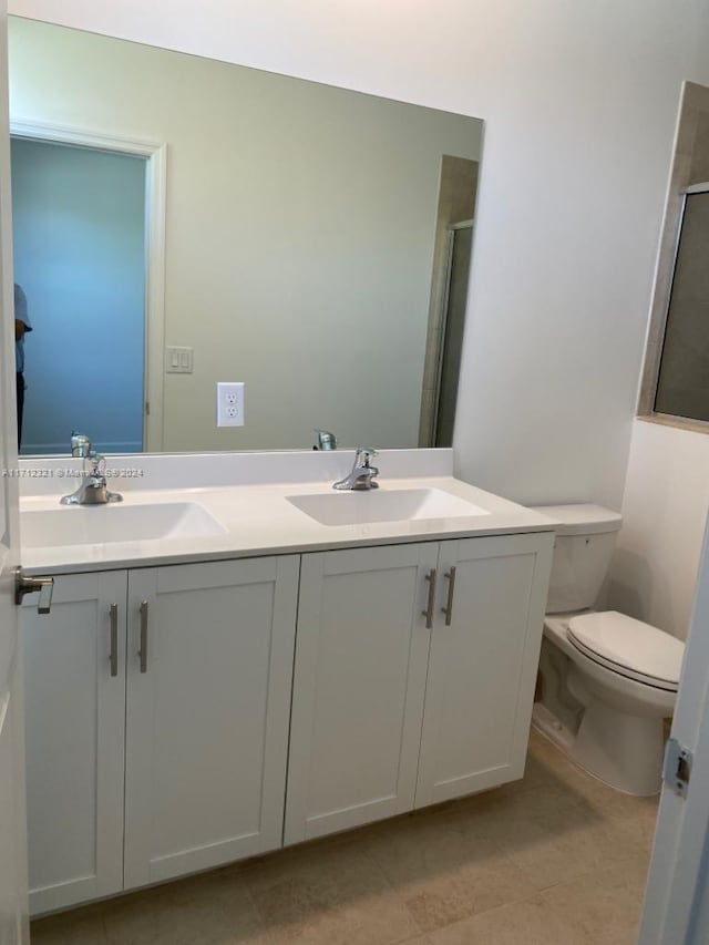 bathroom featuring tile patterned flooring, a shower with door, vanity, and toilet