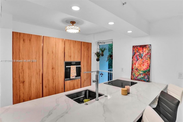 kitchen with sink, light stone counters, kitchen peninsula, oven, and black electric cooktop