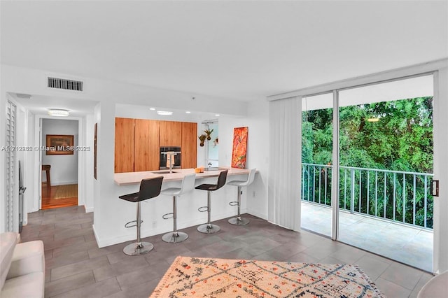 kitchen with a kitchen breakfast bar, floor to ceiling windows, kitchen peninsula, and sink