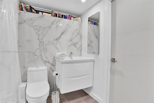 bathroom featuring tile patterned floors, vanity, toilet, and tile walls