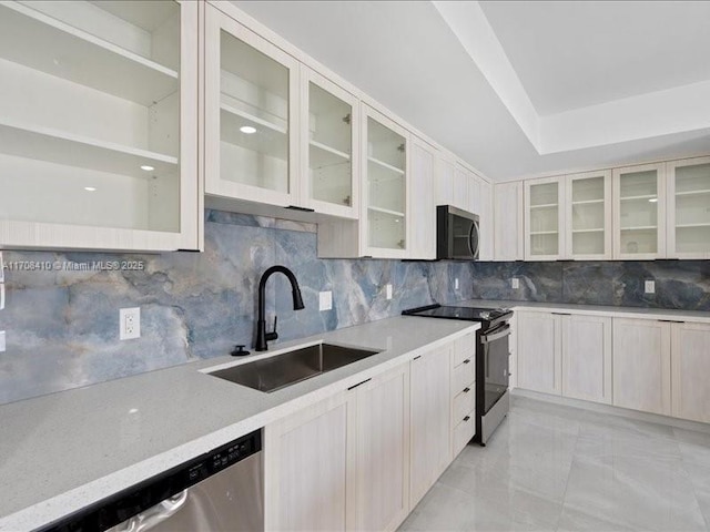 kitchen featuring stainless steel appliances, glass insert cabinets, a sink, and backsplash