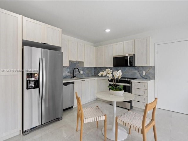 kitchen featuring light tile patterned floors, light countertops, backsplash, appliances with stainless steel finishes, and a sink