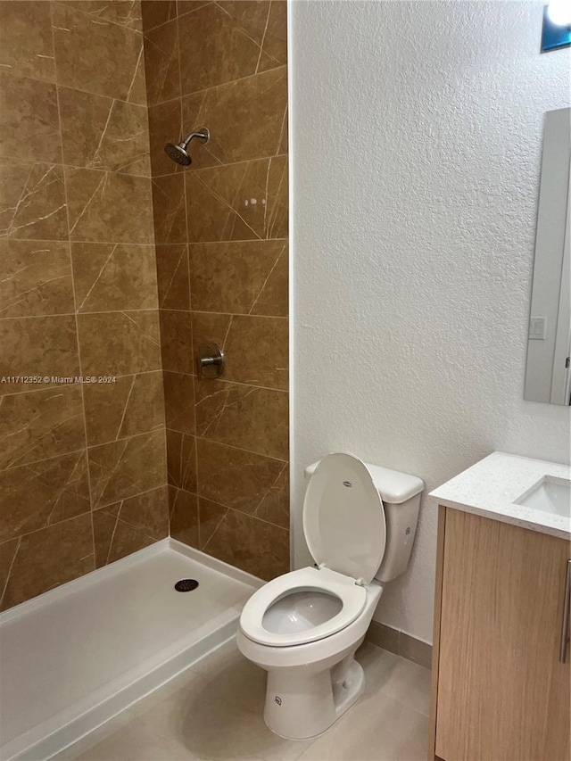 bathroom featuring tiled shower, vanity, and toilet