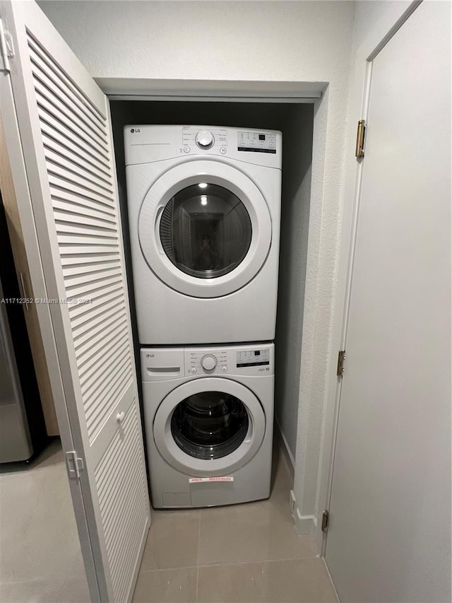 laundry area featuring light tile patterned flooring and stacked washing maching and dryer