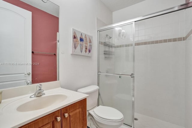 bathroom featuring vanity, toilet, a shower with shower door, and a textured ceiling