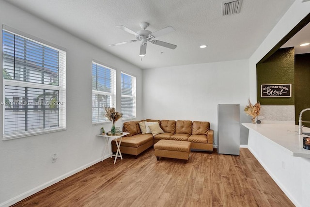 living room with ceiling fan, wood-type flooring, and a textured ceiling